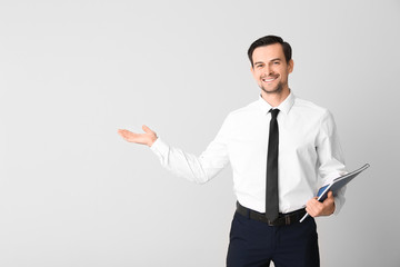Male real estate agent showing something on light background