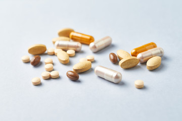 Multicolor vitamins and supplements on bright paper background. Concept for a healthy dietary supplementation. Close up. 