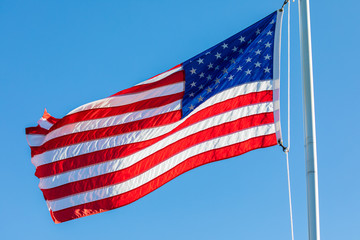 American Flag, backlit by the setting sun, waving in the wind.