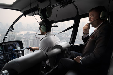 Scene of executive business man on private helicopter while flying over the sky among high...