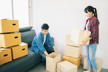 Young couple Asian man and woman Packing boxes and carrying large packed carton cardboard boxes on moving day at new home  luxury house or apartment.Moving house concept