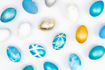 Top view of easter eggs colored with golden paint in different patterns. Various striped and dotted designs. White background