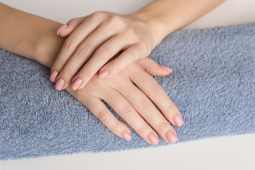 Preparation for manicure. The hands of a young girl lie on a classic blue towel on the table. Nude manicure. Hand care