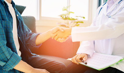 Doctor and patient shaking hands in office, they are sitting at desk, discussing something ,Having Consultation,Medical physician working in hospital writing a prescription, medically  Healthcare