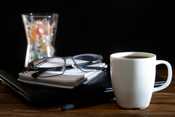 Cup of coffee with laptop notepad and glasses on a wooden table