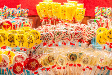 Fototapeta na wymiar Many colored lollipops, round or squared packed in transparent bags