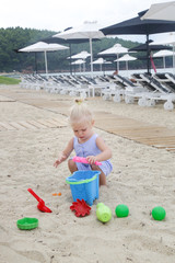Happy toddler girl playing with toys outdoor in the sand