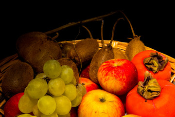 Cesto di frutta su sfondo nero. Natura morta.