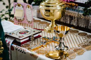Holy Bible, crown, cross, bowl, crown  on table in church ready for ceremony. close up.