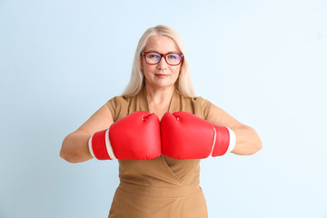 Woman in boxing gloves on color background. Concept of feminism