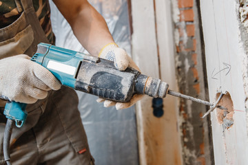 Builder man cutting electrical chase in concrete wall with hammer drill diamond crown