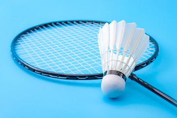 Competitive sports and high performance in tournament match conceptual idea with badminton rackets and shuttlecock (birdie) isolated on blue court background
