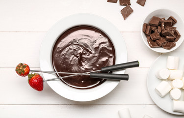 Bowl with tasty chocolate fondue, strawberry and marshmallow on table