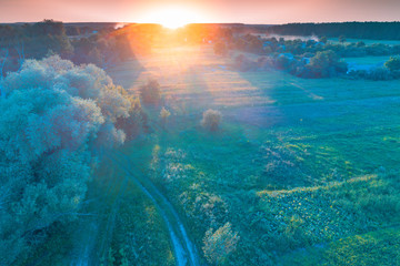 Fototapeta na wymiar Aerial view of the countryside at sunrise. Dirt country road and arable fields. Beautiful nature landscape