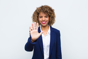 young woman african american smiling and looking friendly, showing number five or fifth with hand...