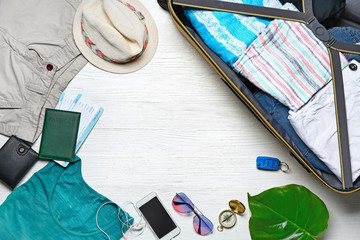 Set of male accessories and suitcase on white wooden background. Travel concept