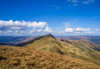 Colorful mountain landscape in the summer mountains. Large hills with blue sky.
