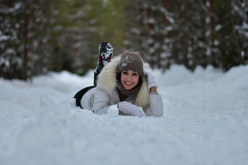 Fototapeta na wymiar Beautiful girl in the winter frosty forest lies in the snow