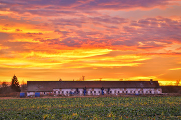 Old farm building under the red sky on sunset