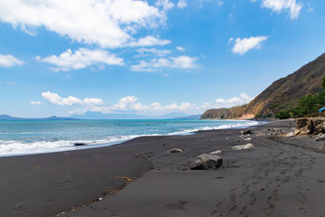 Black sand beach and wave of sea with mountain background at Ende , Indonesia.