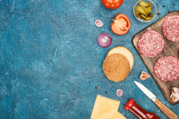 Obraz na płótnie Canvas top view of fresh cheeseburger ingredients on blue textured surface