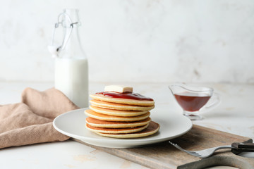 Plate with stack of tasty pancakes on table