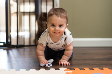 Baby boy crawling and smiling in front of a baby gate