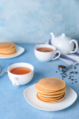 Plate with tasty pancakes and tea on table