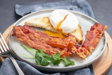 Breakfast - fried bacon pieces and poached eggs on a plate.