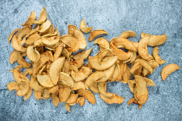 A handful of dried Apple slices close up on a gray textured surface