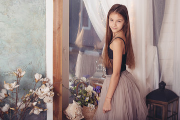 a pretty teenage brunette girl with long hair stands near the mirror, a concept of youth and...