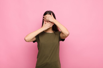 young pretty woman covering face with both hands saying no to the camera! refusing pictures or...