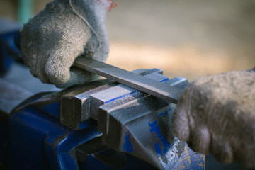 A man using the steel rasp to decorate the work , the hammer to sharpen