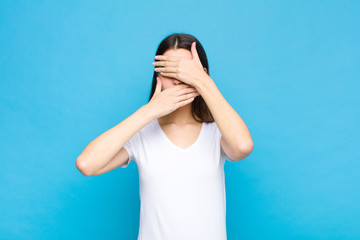 young pretty woman covering face with both hands saying no to the camera! refusing pictures or...