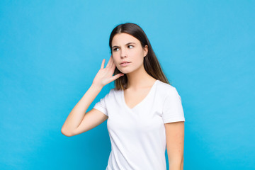 young pretty woman looking serious and curious, listening, trying to hear a secret conversation or...