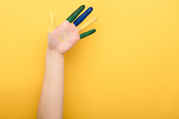 cropped view of woman with colorful fingers on yellow background