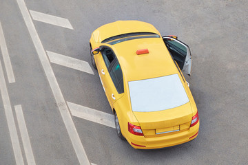 Yellow taxi car on the pavement with an open door, top view