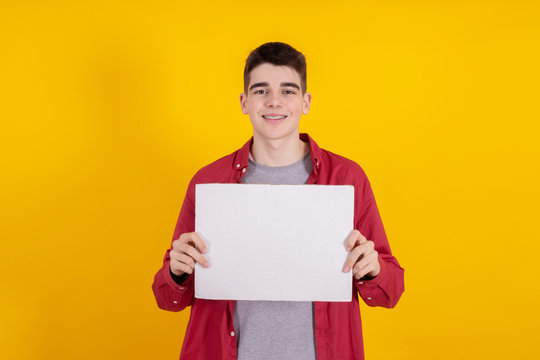 young teenager boy holding sign or signboard isolated on color background