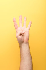 cropped view of man showing four fingers on yellow background
