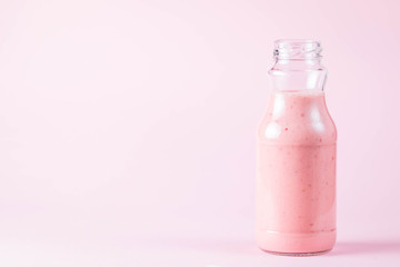 Glass of fresh strawberry milkshake, smoothie and fresh strawberries on pink, white and wooden background. Healthy food and drink concept.