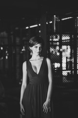 Beautiful sexy european brunette girl in evening red dress in standing near window and lattice in interior in cafe. Looking into camera serious. Poses. Upper half of body. Close Up. black white photo