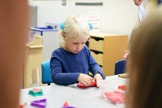 Little Preschool age Child Playing with Clay at School