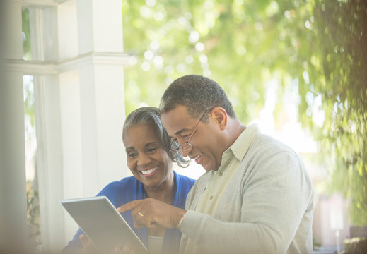 Happy senior couple using digital tablet on porch