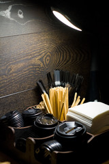 Against dark background in the coffee shop there is an organizer, a bar stand for napkins, tubes and covers for disposable cups.