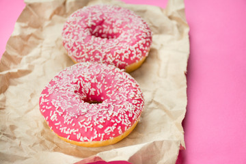 Sweet donuts with pink glaze over pink background.Fashionable color and style. Flat lay. Copy space.