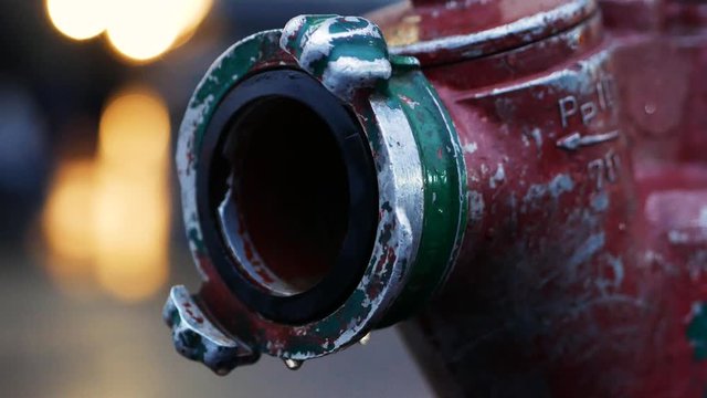 Waterdrops dripping from a leaking fire hydrant during a fire fighting operation. Close up 4k