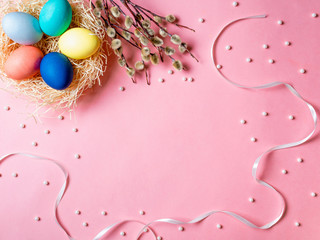 Orthodox Easter concept. Colorful eggs and pussy willow branches on pink background with empty chalkboard. Copy space for greetings, text or design. Top down view or flat lay