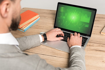 partial view of businessman using laptop with marketing information on screen isolated on grey