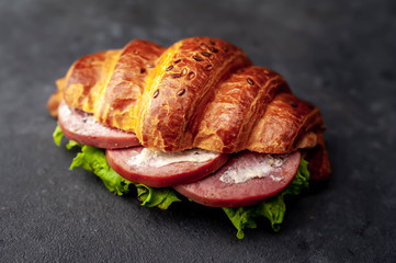 croissant sandwich with sausage and cheese on concrete background