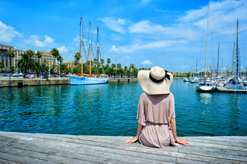 Young traveler girl sit on a pier in Barcelon
